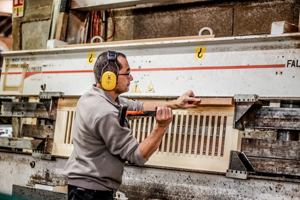 Homme travaillant sur une machine avec des volets Guignard en bois.